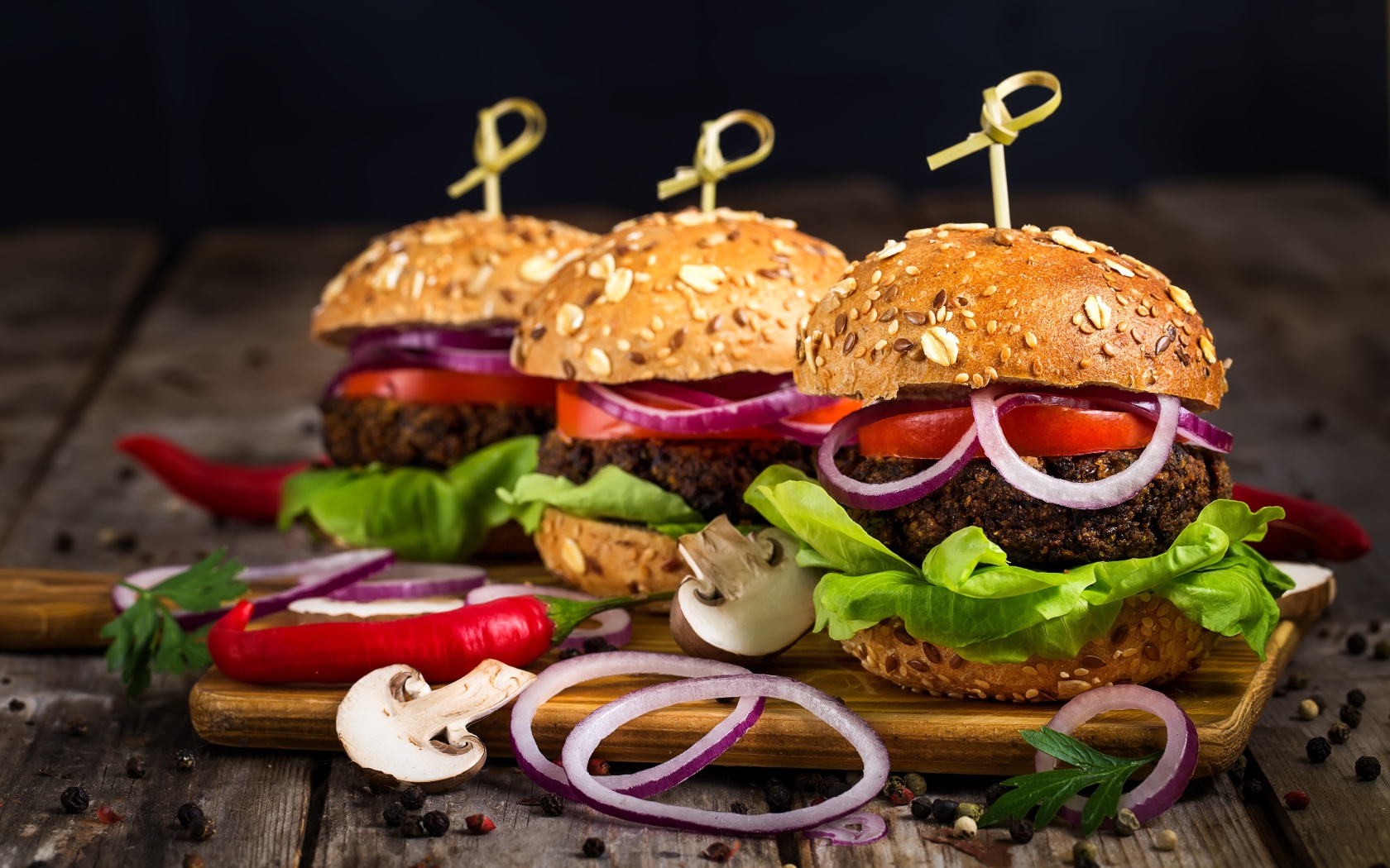 Три аппетитных гамбургера с кольцами лука и перцем