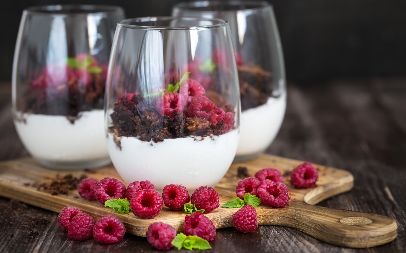 Десерт со сливками, шоколадом и свежей малиной в стеклянных стаканах
