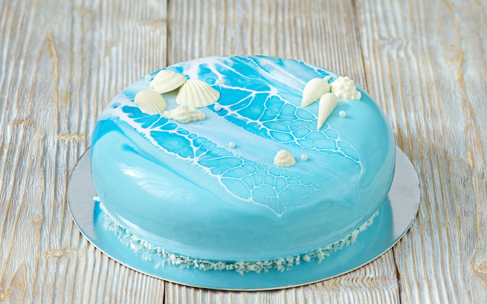 Глянцевый торт голубого цвета украшен сахарными ракушками