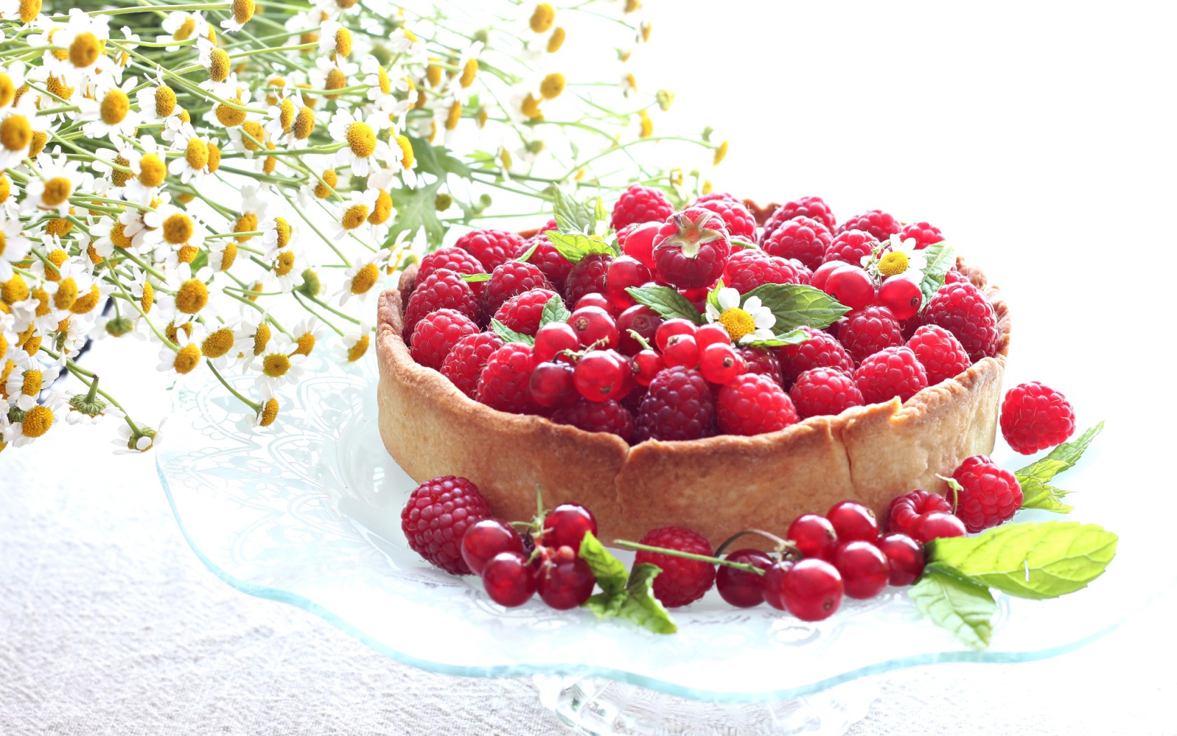 Пирог с ягодами малины и смородины на столе с ромашками