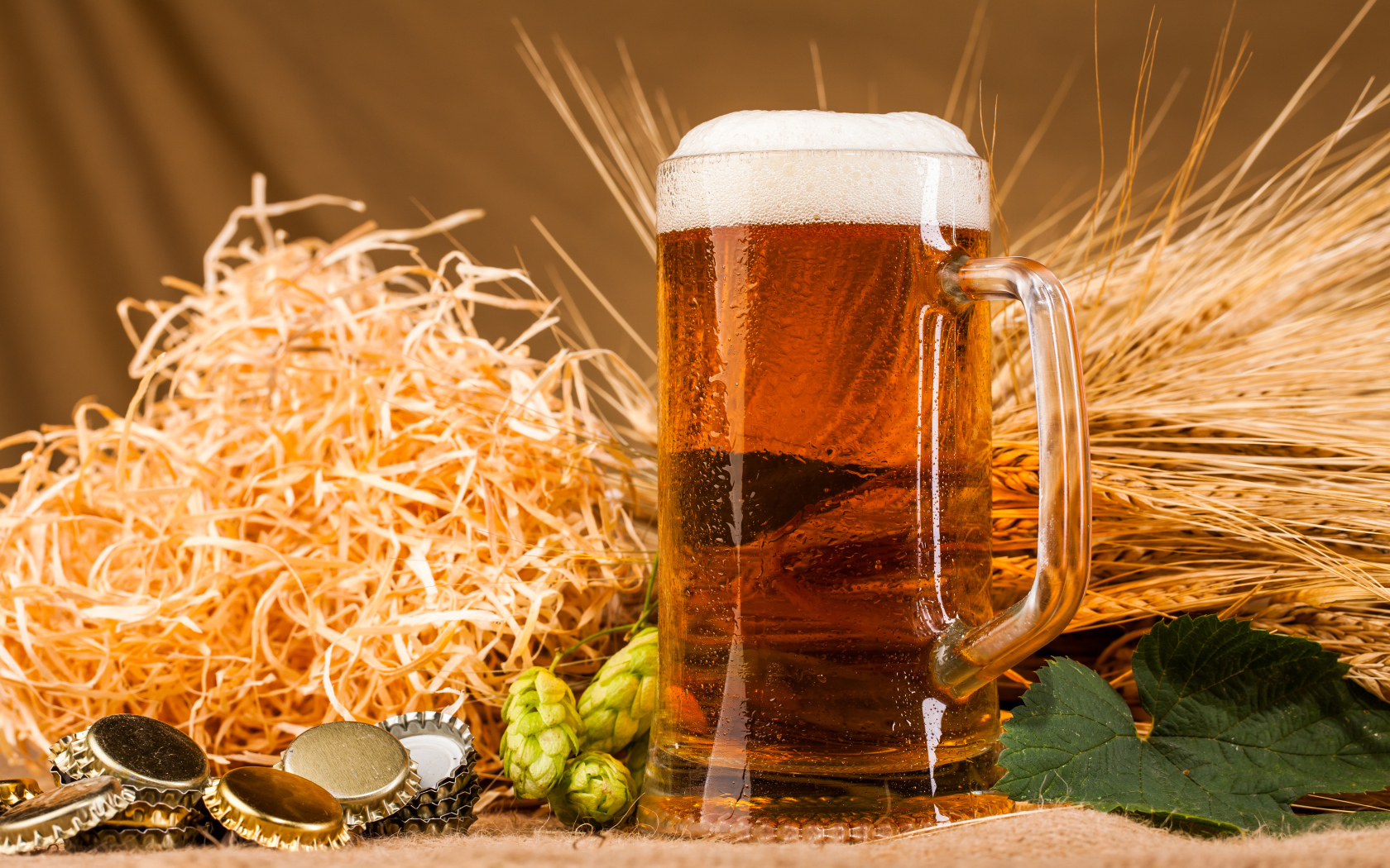 Бокал пива с пеной на столе с хмелем и соломой