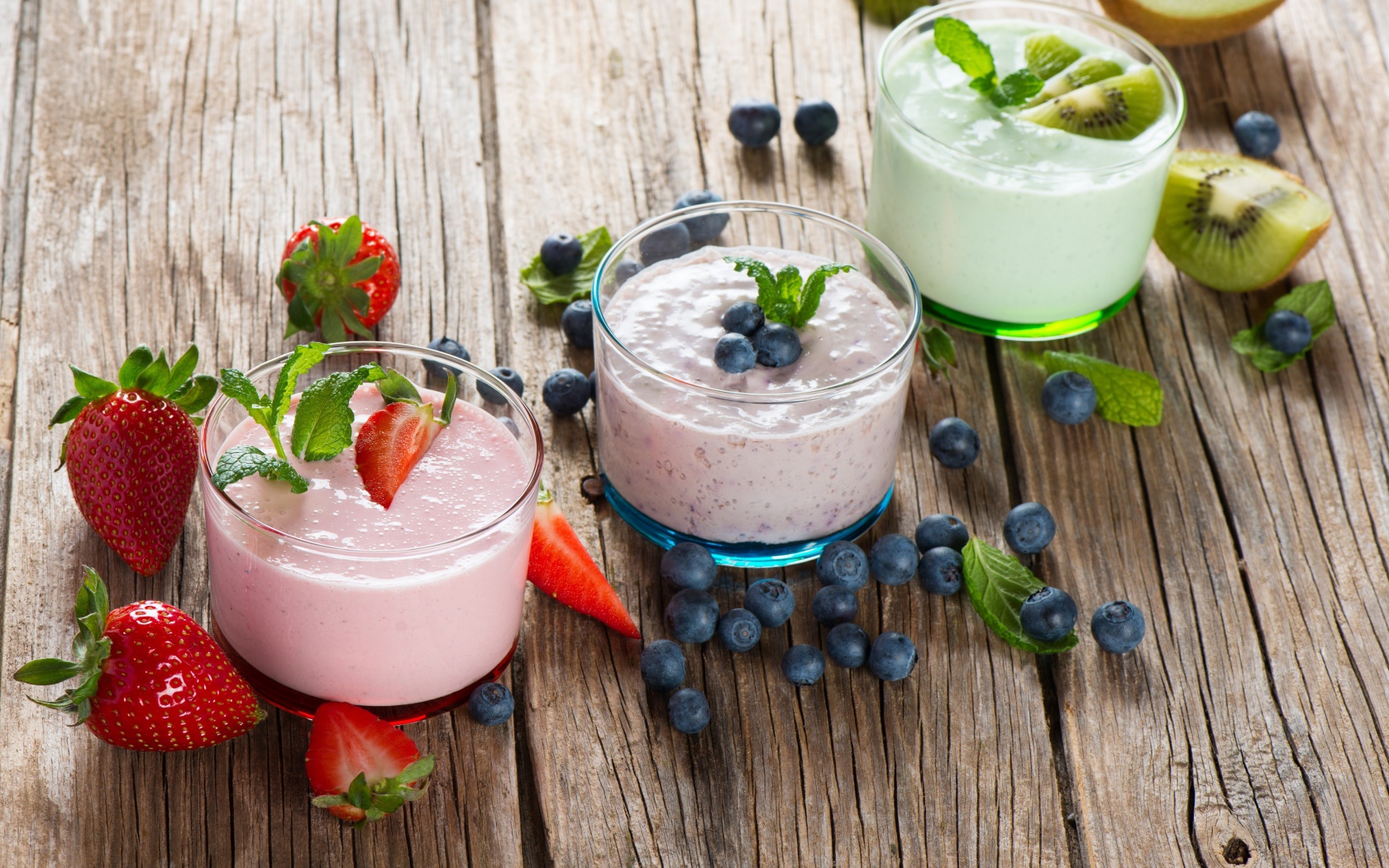 Три стакана смузи с клубникой, киви и черникой и свежими ягодами