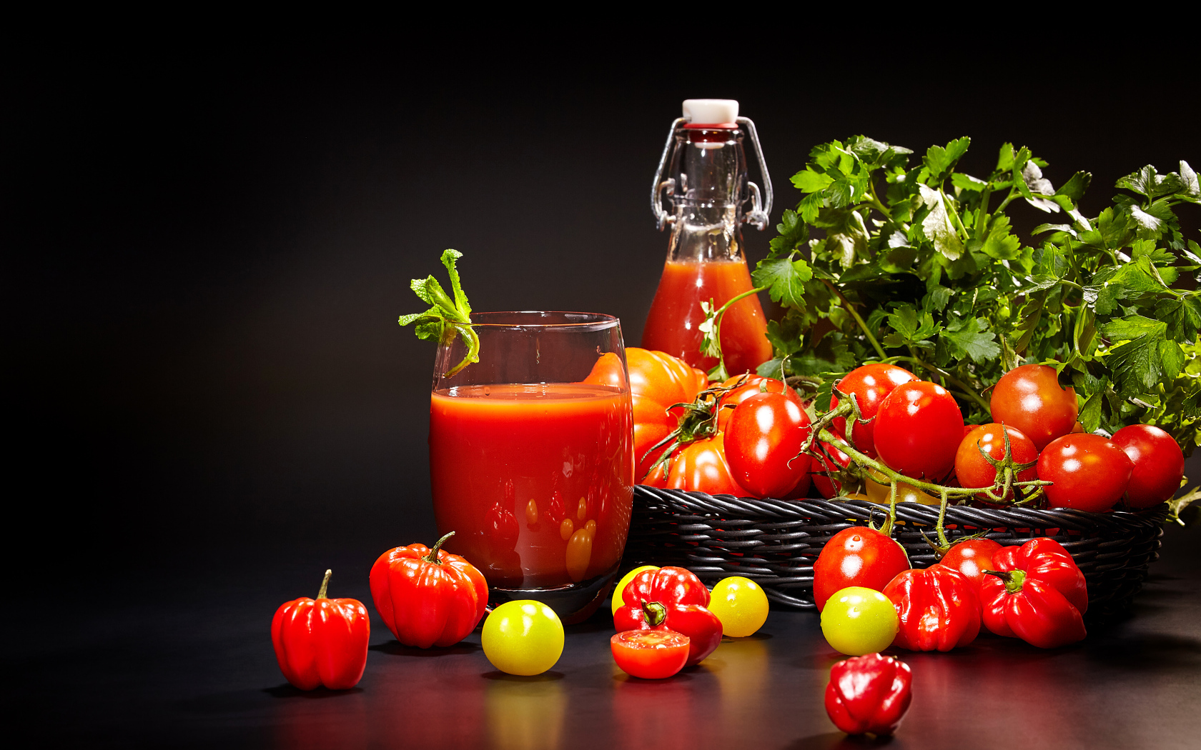 Томатный сок и свежие помидоры на столе на черном фоне