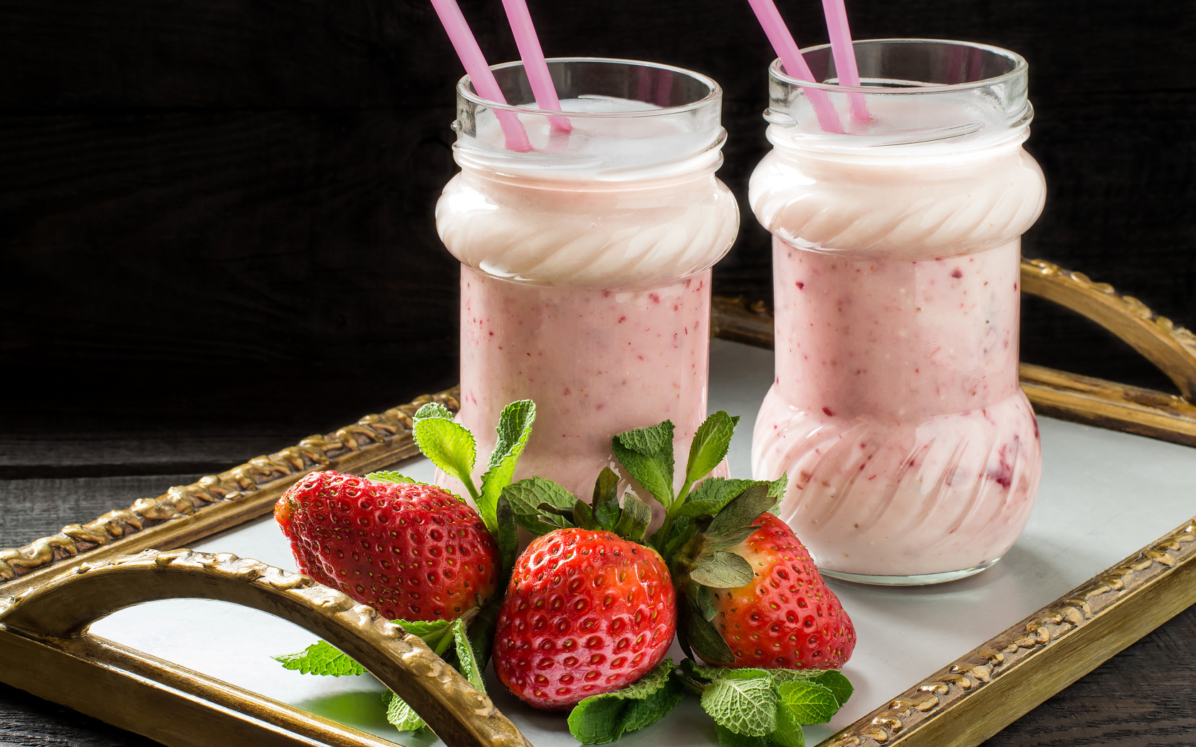 Два свежих клубничных коктейля с трубочками и ягодами клубники