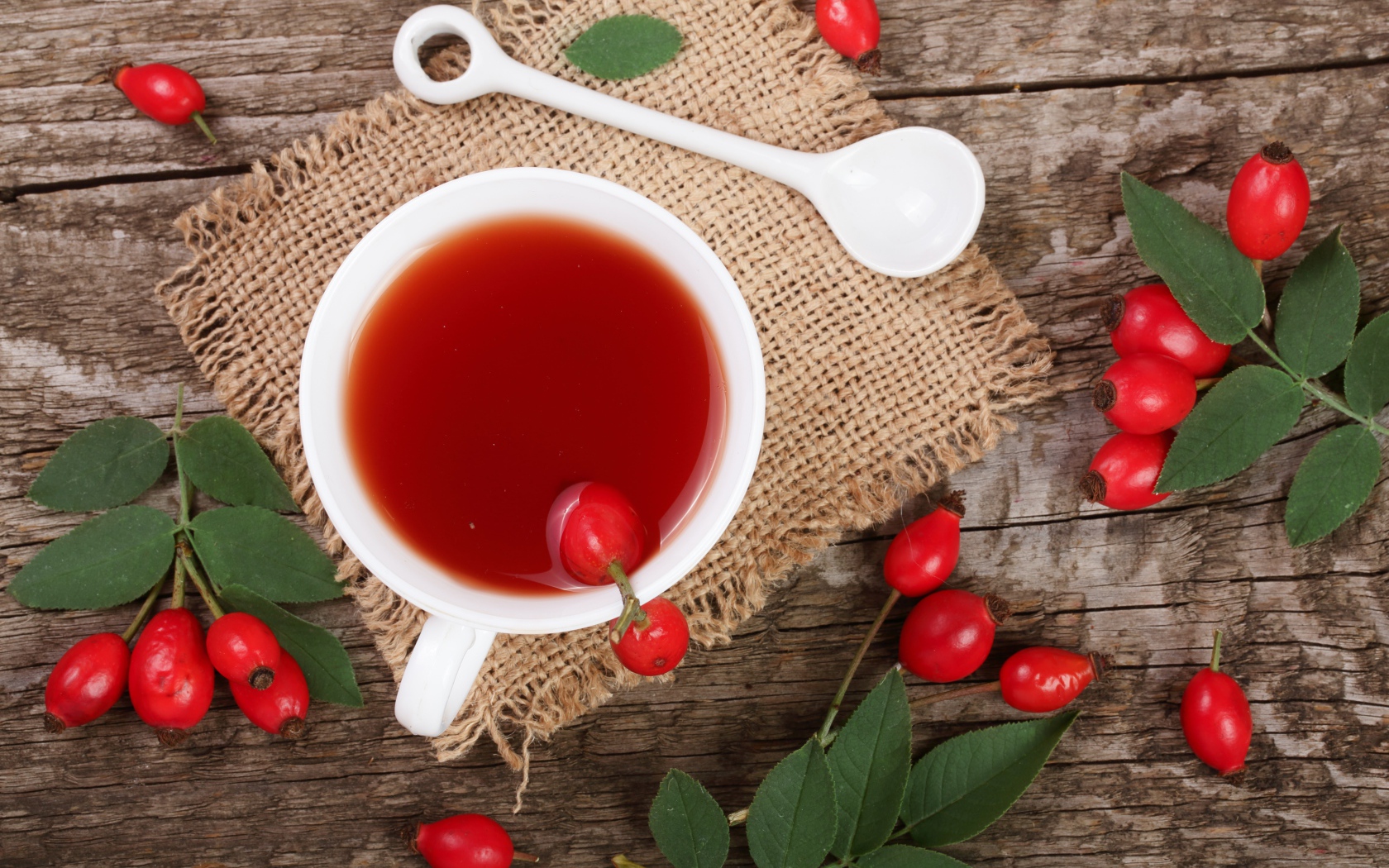 Белая чашка чая с ягодами шиповника на столе