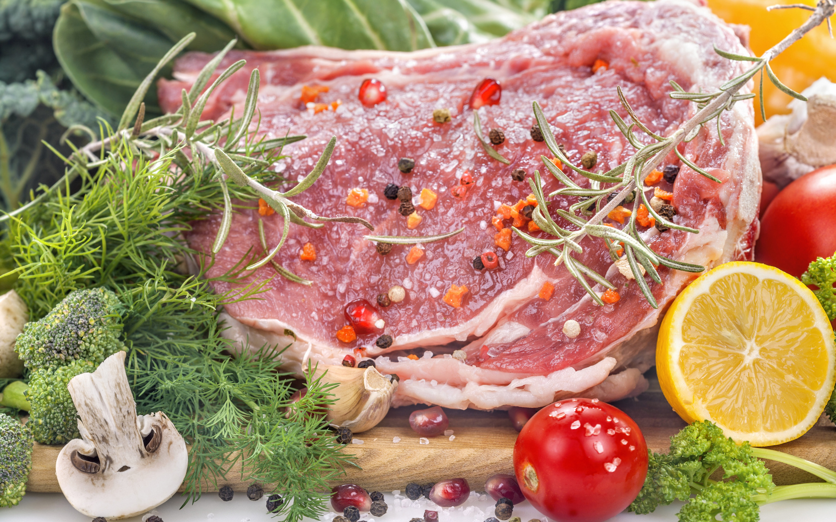 Кусок свежего мяса со специями и зеленью на разделочной доске