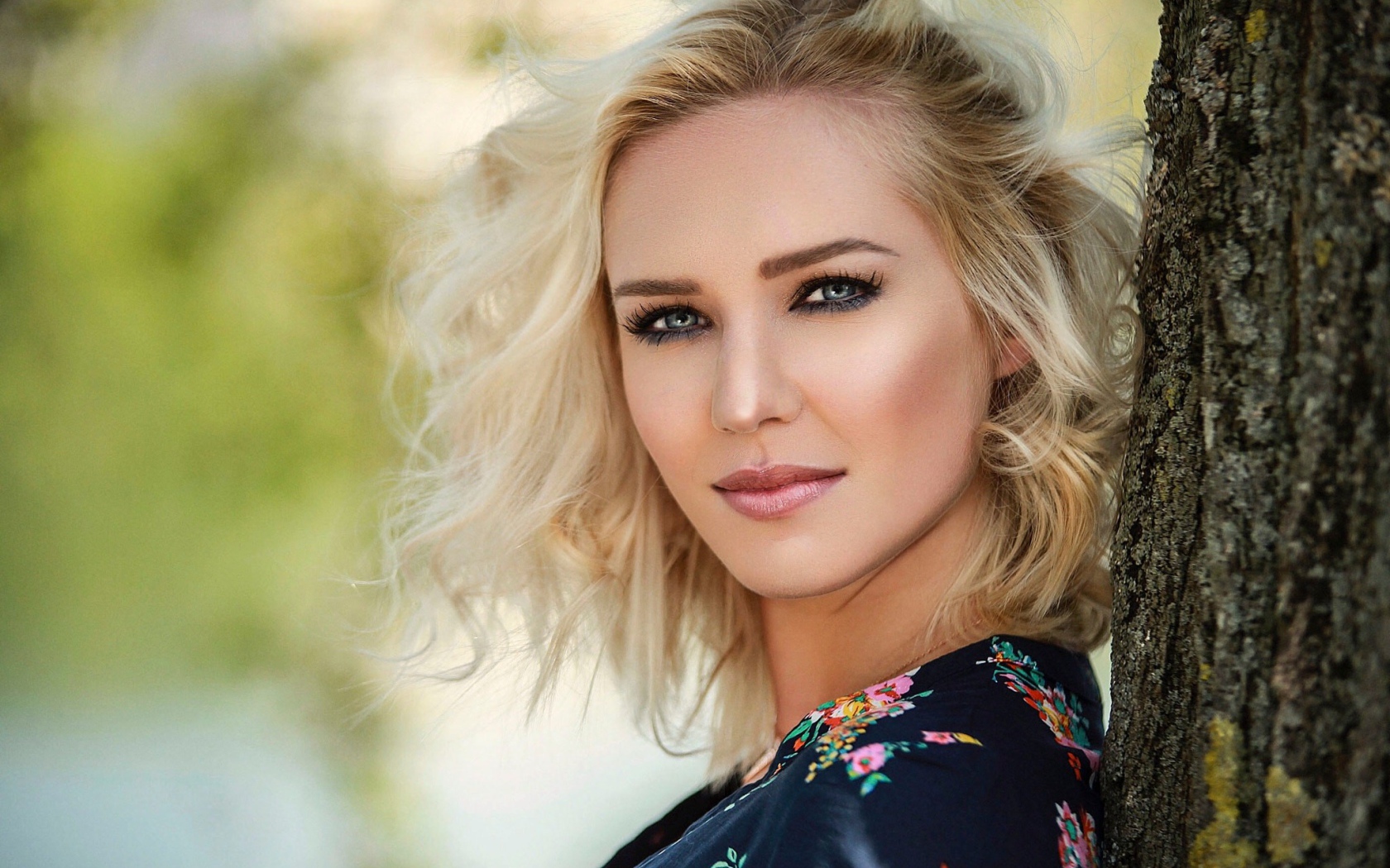Красивая блондинка с голубыми глазами у дерева 