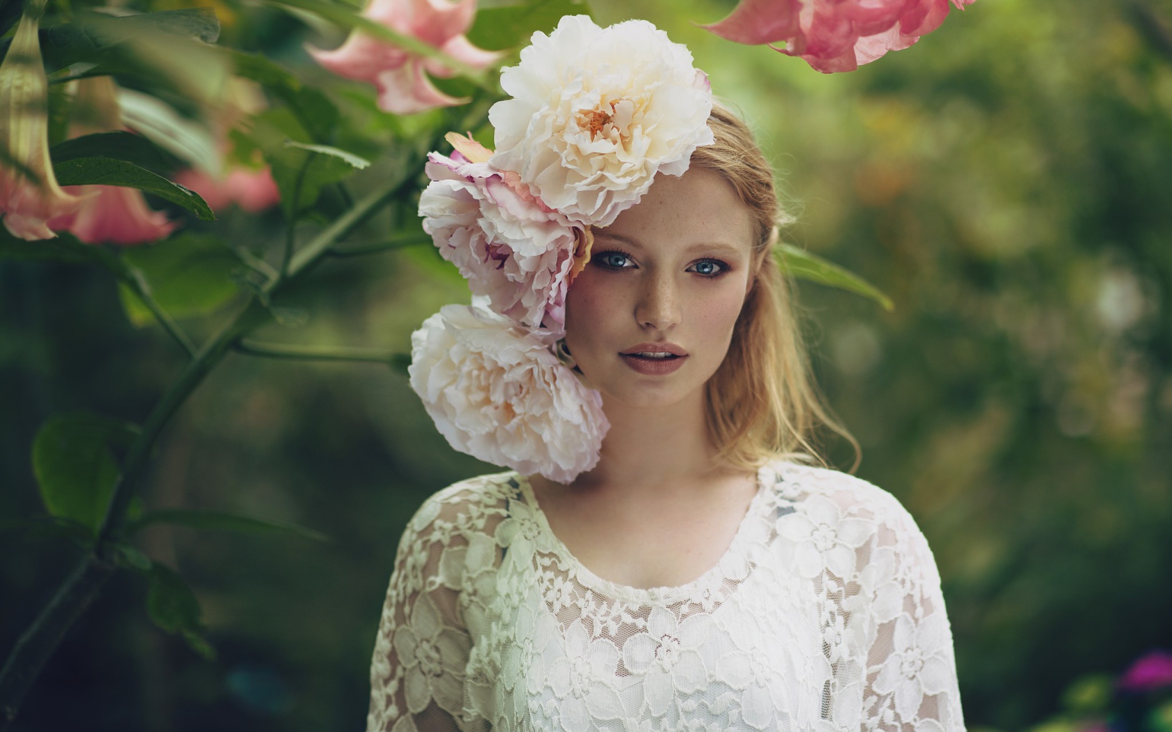 Красивая девушка в белом платье с большими пионами в волосах 