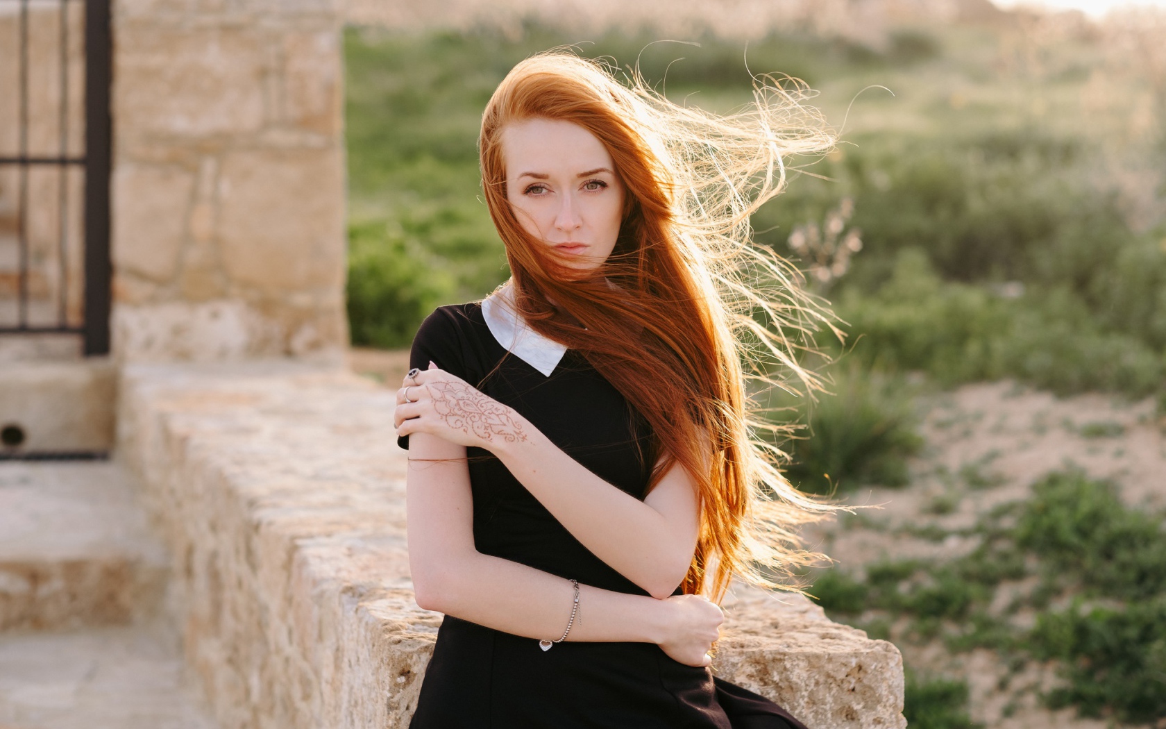 Красивая рыжеволосая девушка в черном платье с рисунком на руке