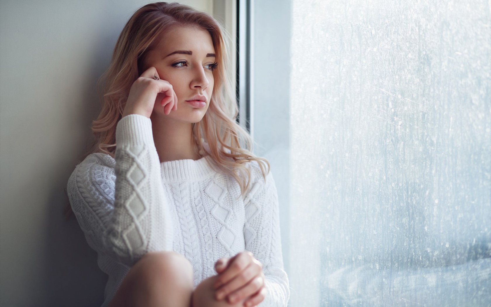 Молодая девушка блондинка у окна 