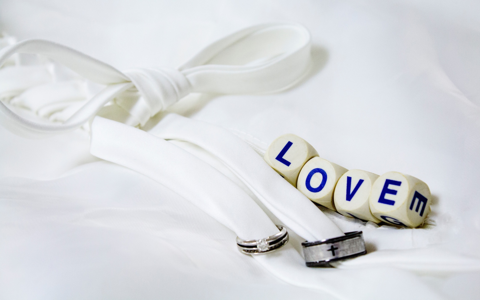 Два кольца перевязанные белой лентой и кубики с надписью любовь