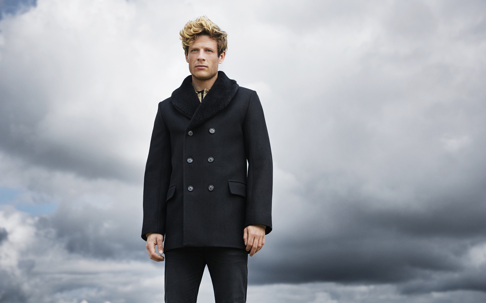 Актер Джеймс Нортон в черном пальто на фоне неба