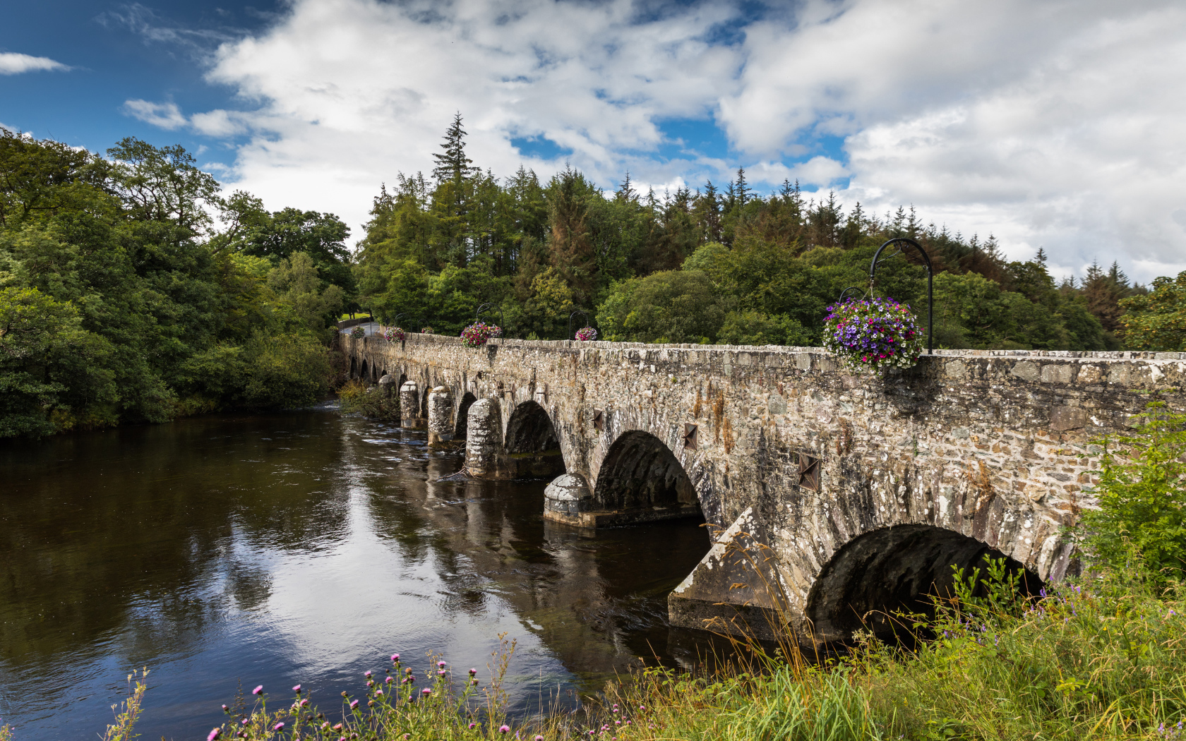 Мост через реку у леса на фоне красивого голубого неба с белыми облаками. Ирландия