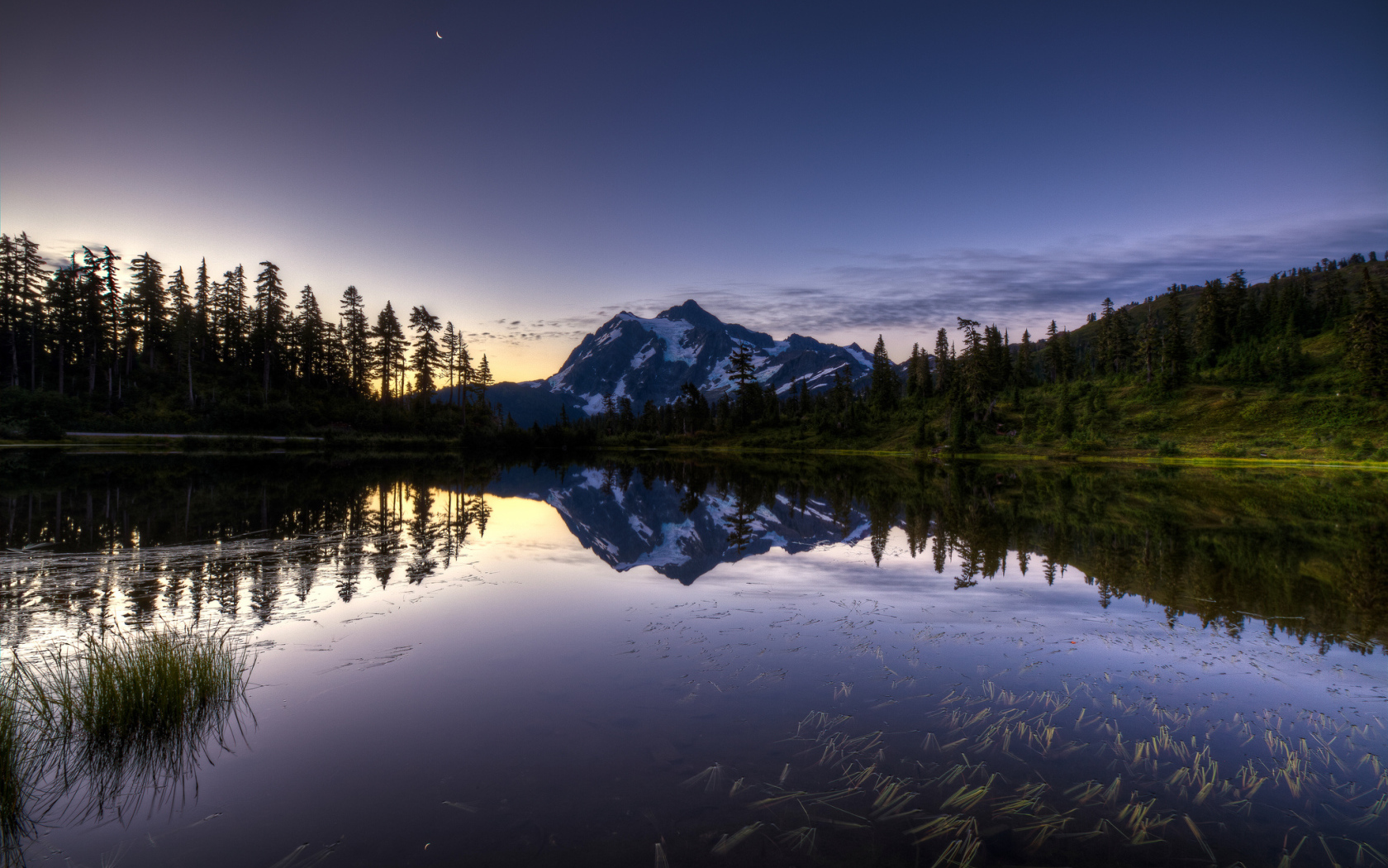 Заснеженная гора и лес отражается в озере вечером