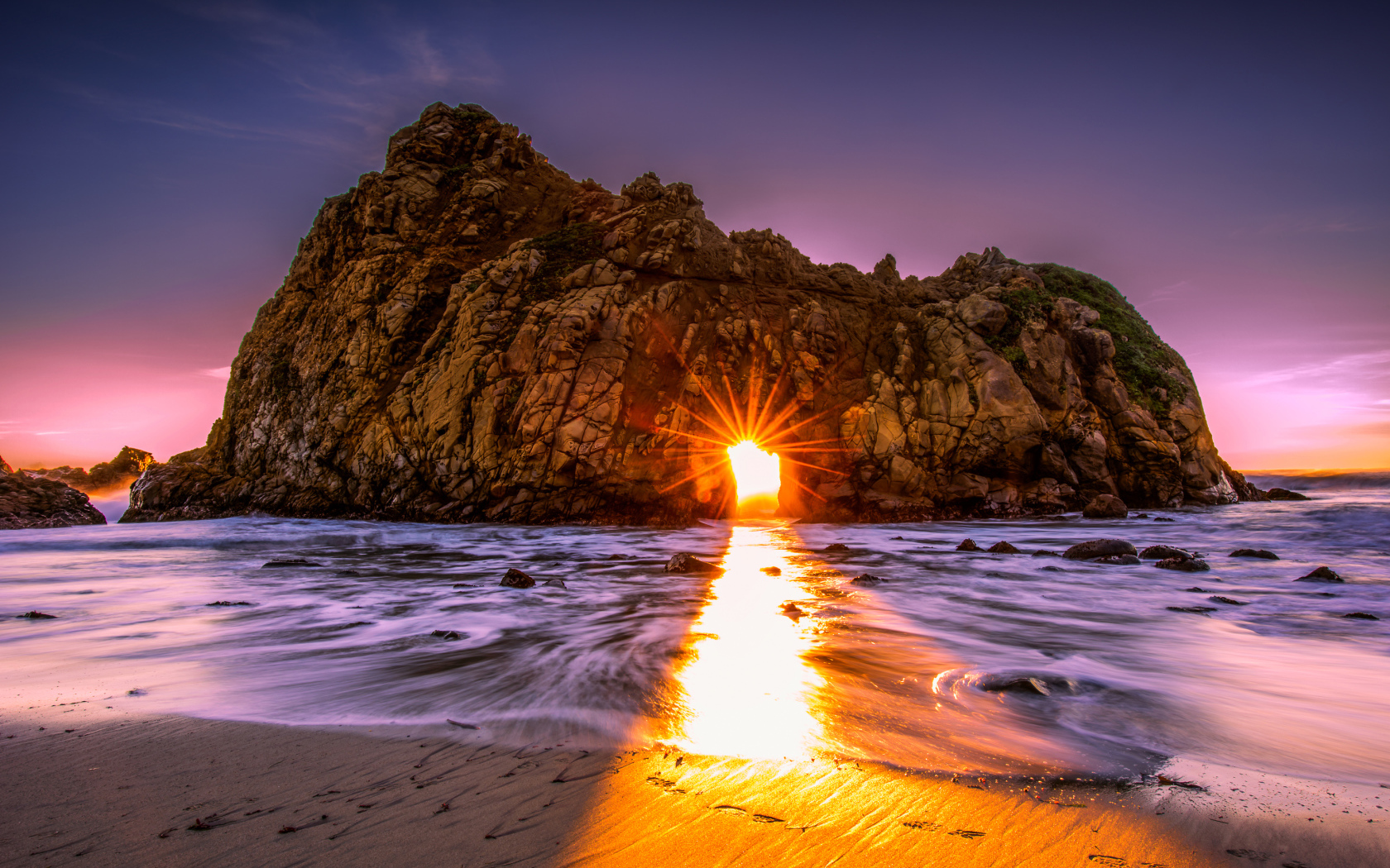 Лучи солнца пробиваются сквозь отверстие в скале  Pfeiffer Beach Big Sur, Калифорния  