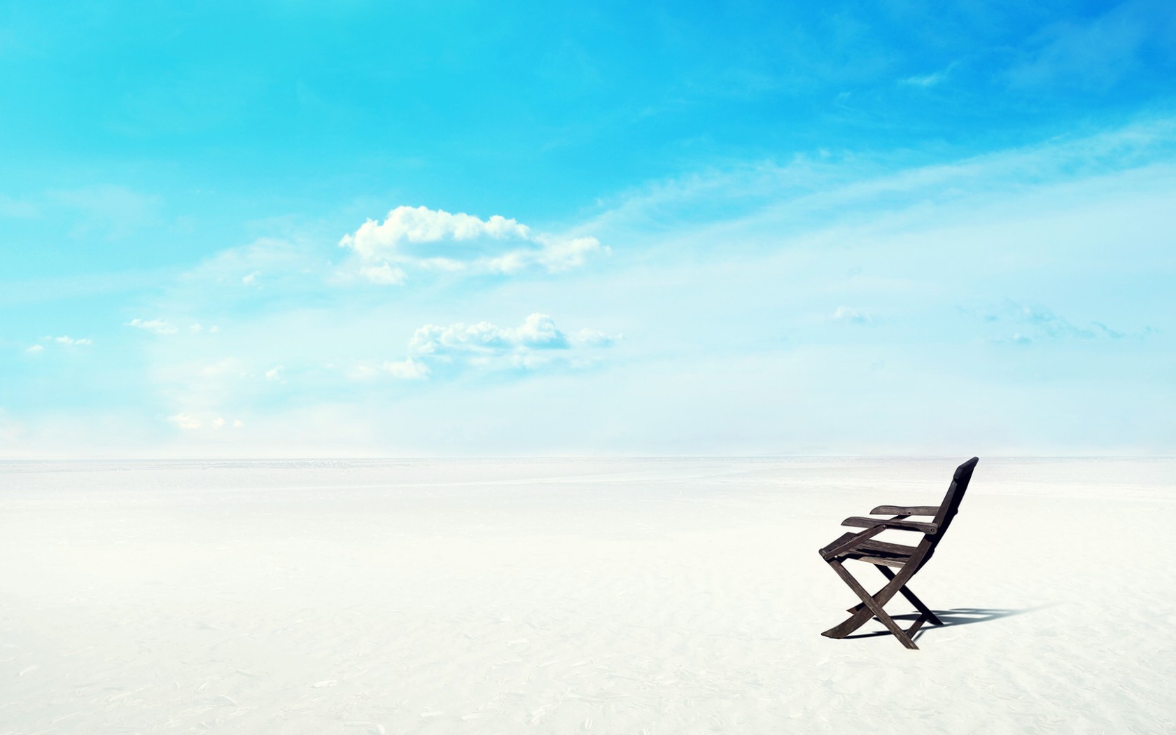 Шезлонг на белом песке на фоне голубого неба