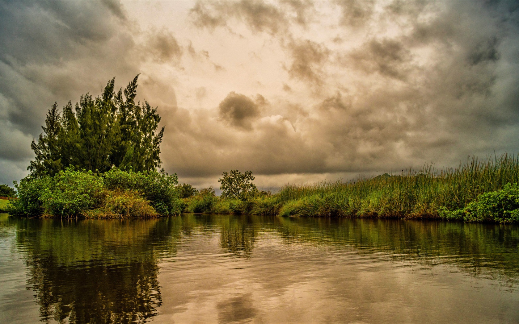 Облака над озером с покрыми зеленой травой берегами