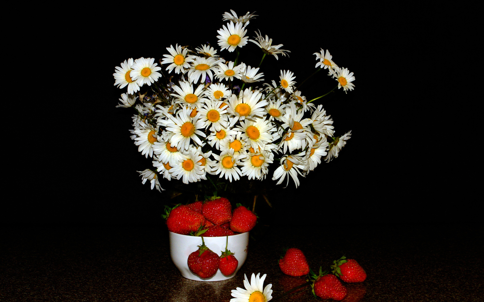 Белые полевые ромашки и клубника на столе на черном фоне