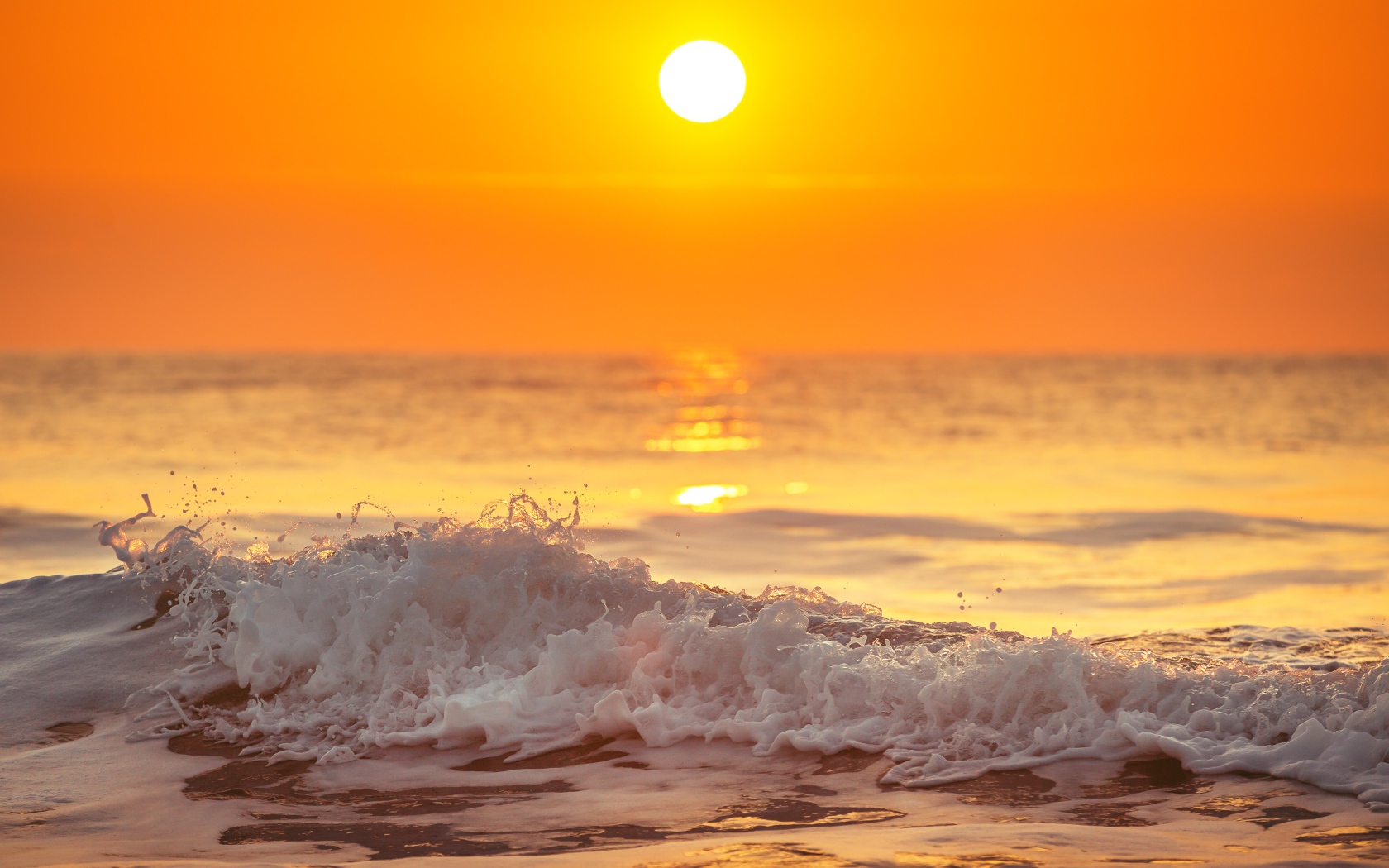 Белая пена на морском берегу в свете солнца на закате