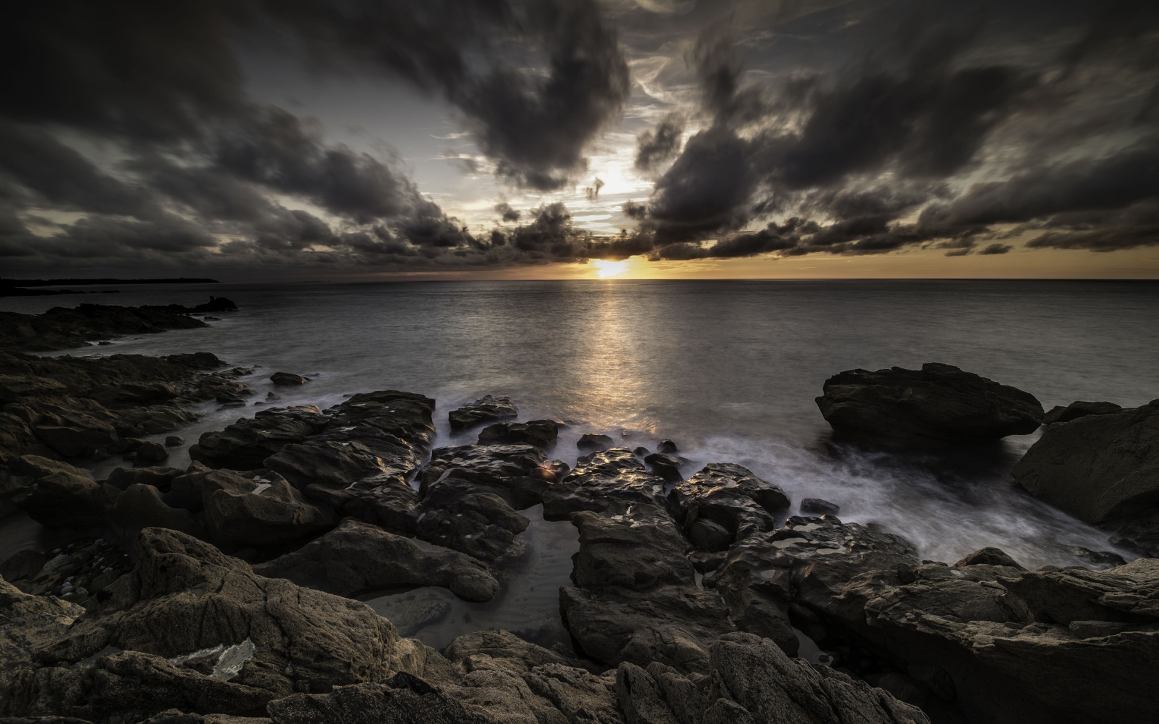 Низкие черные облака на закате в небе над океаном