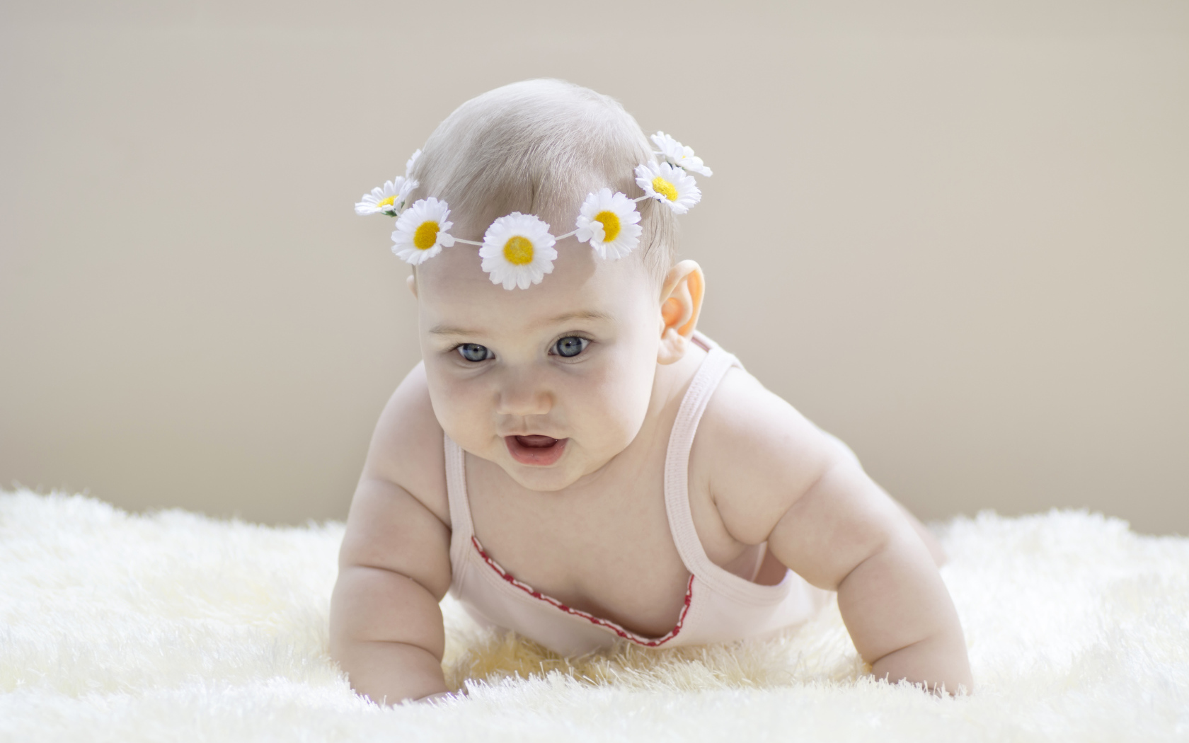 Грудной ребенок с венком из белых ромашек на голове