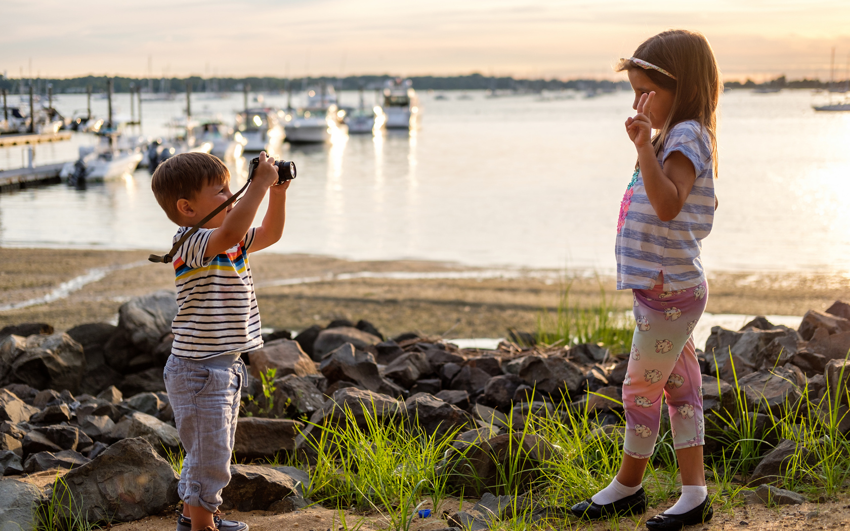 Маленький мальчик фотографирует девочку на берегу