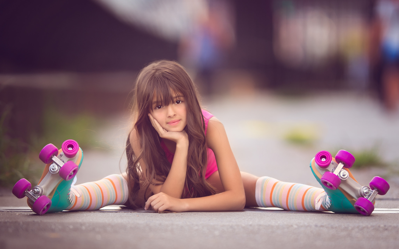 Маленькая девочка сидит на дороге в роликах