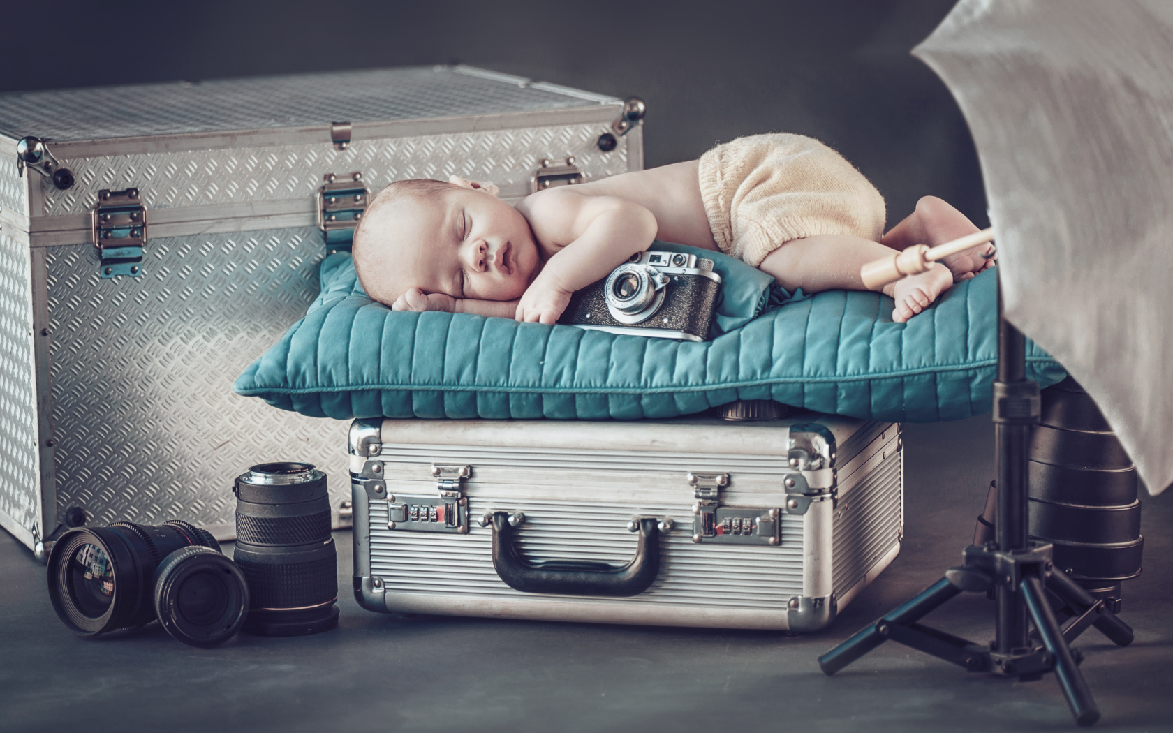 Спящий младенец с фотоаппаратом спит на чемодане