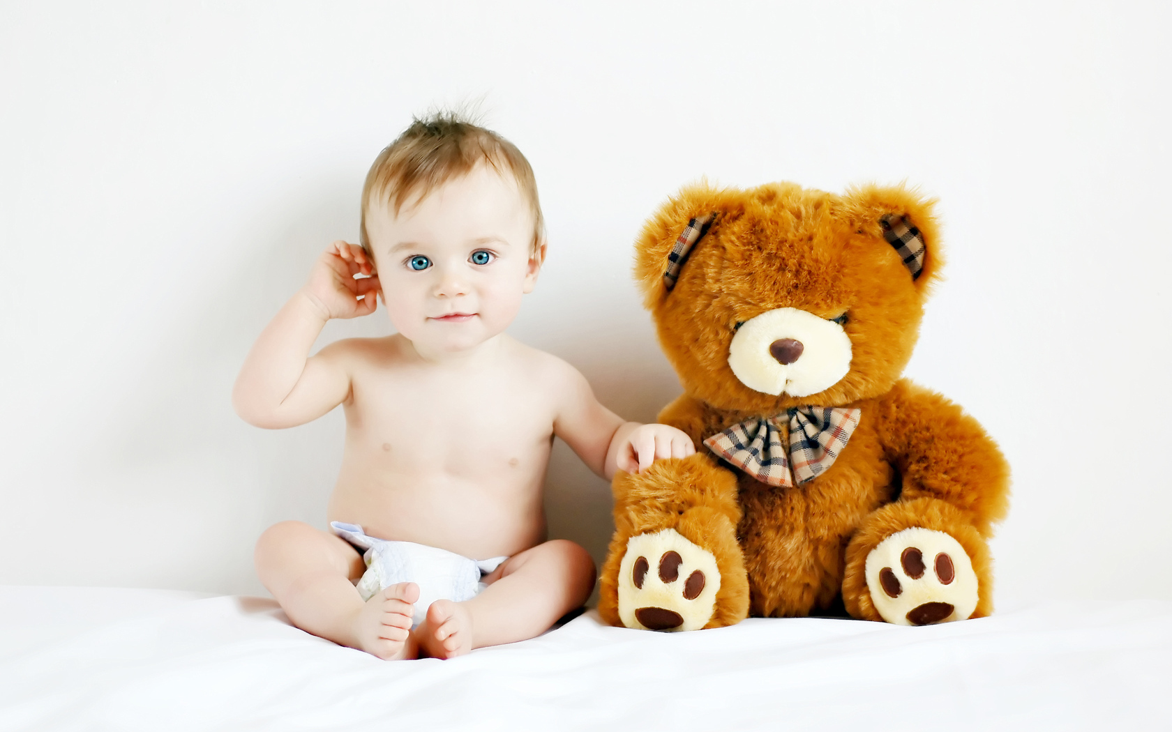 Маленький голубоглазый ребенок с большим плюшевым медведем