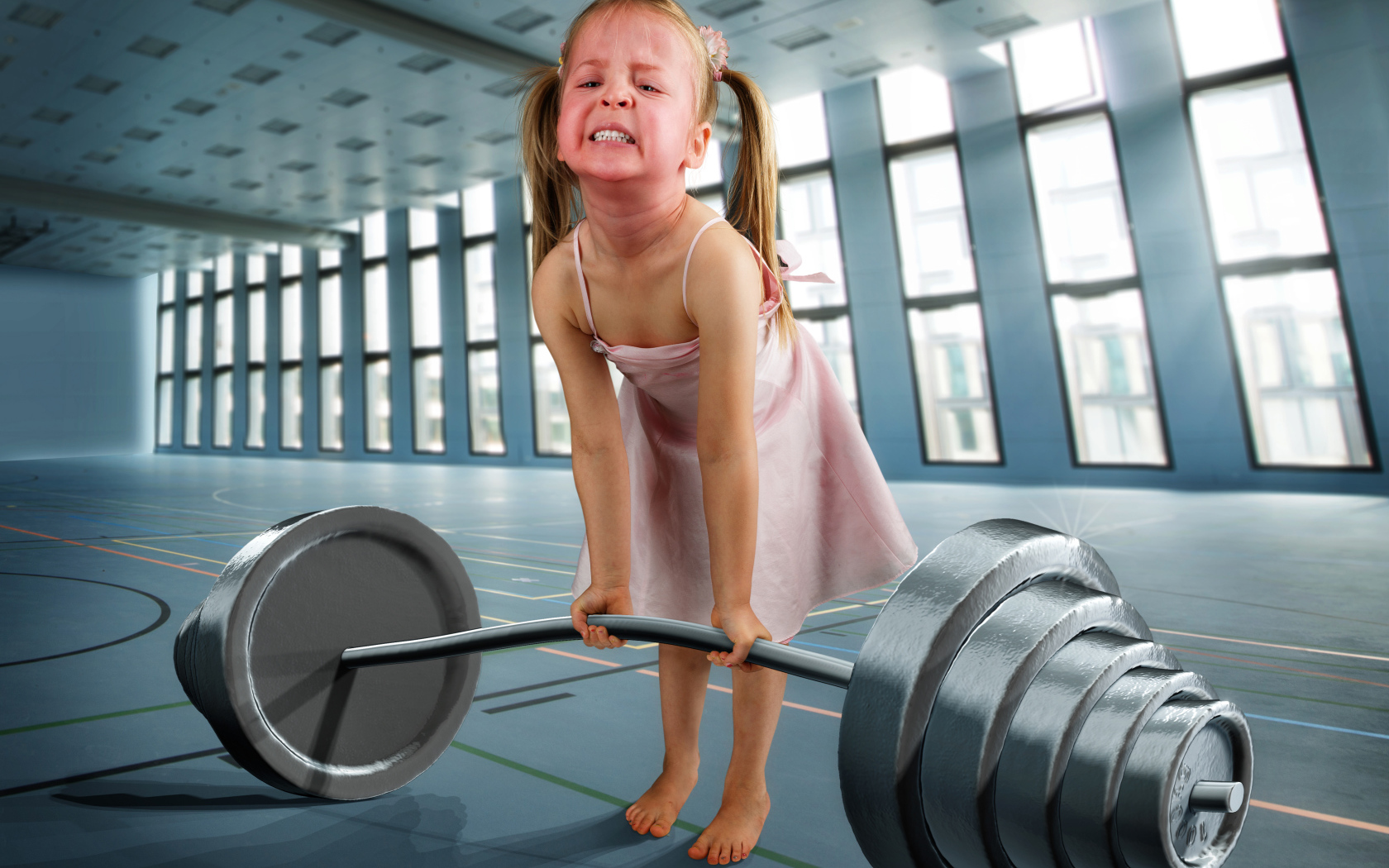 Смешная девочка пытается поднять тяжелую штангу