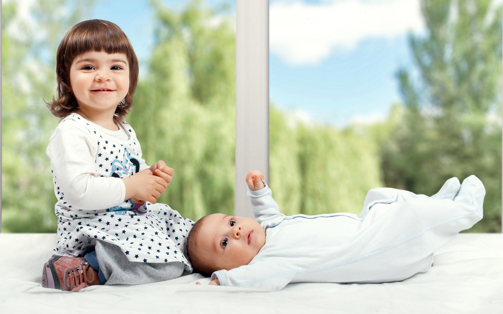 Маленькая улыбающаяся девочка с грудным ребенком