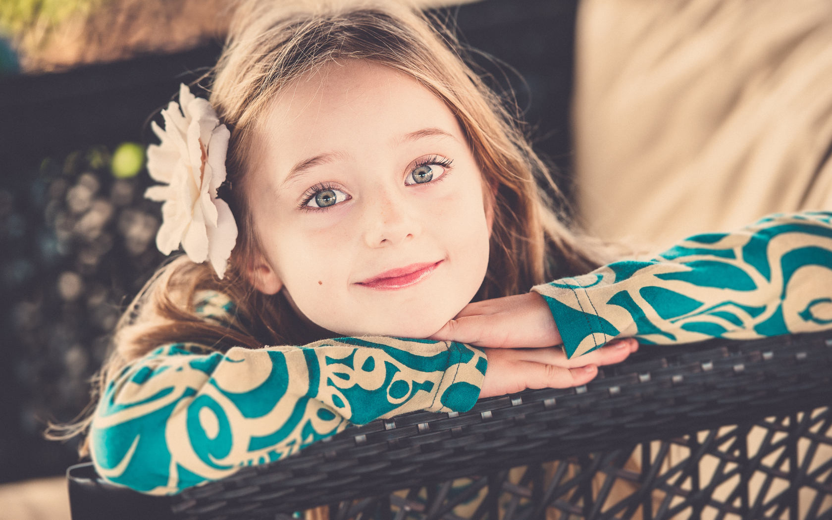 Улыбающаяся зеленоглазая девочка с белым цветком в волосах