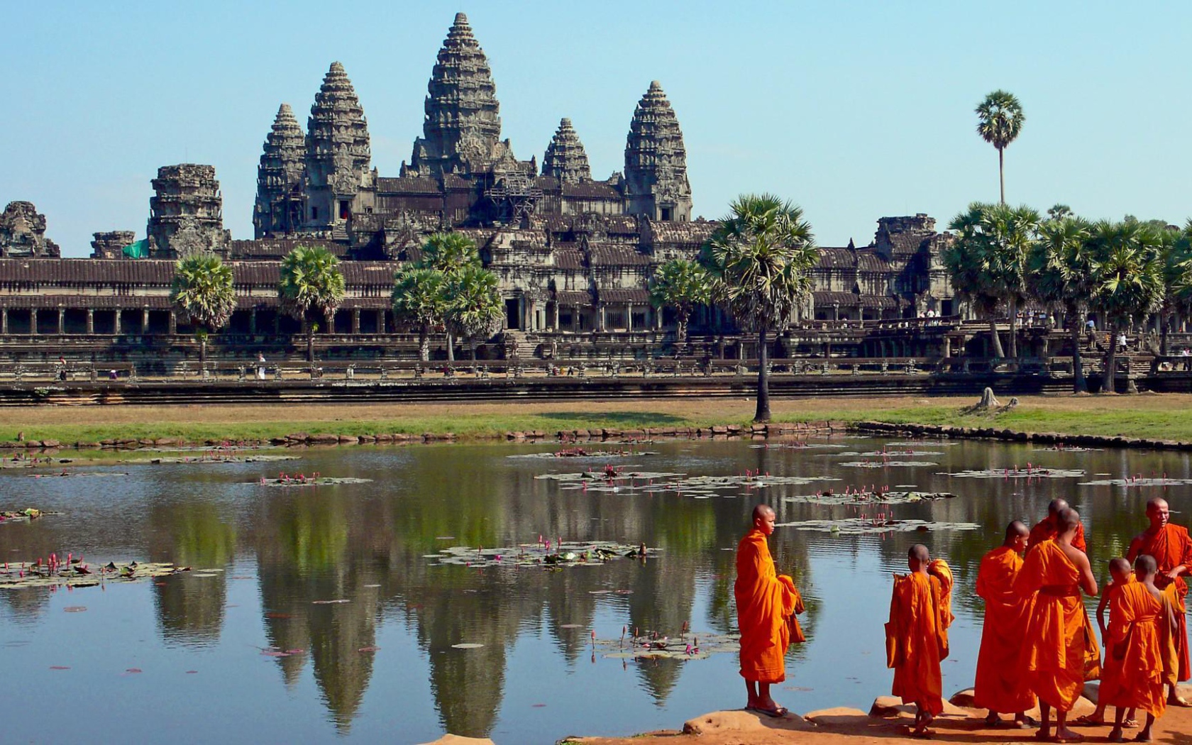 Монахи на берегу водоема у храмового комплекса Ангкор Ват 