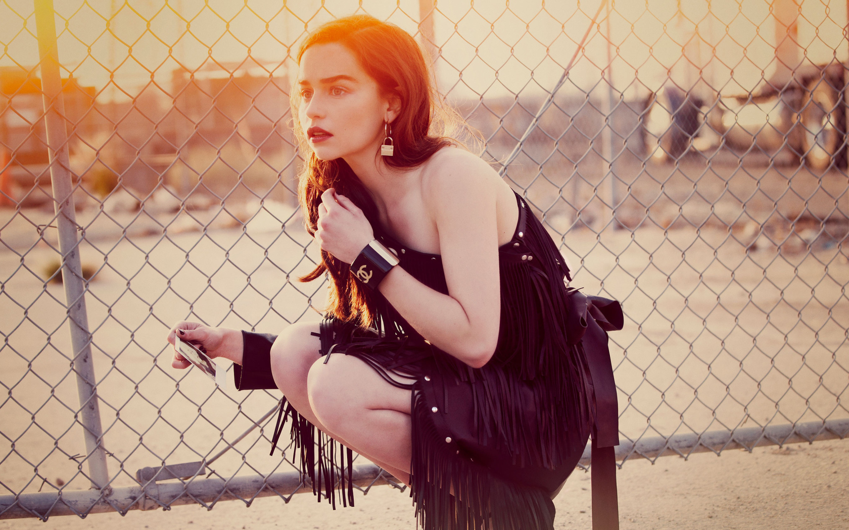 Актриса Эмилия Кларк в красивом черном платье в лучах солнца