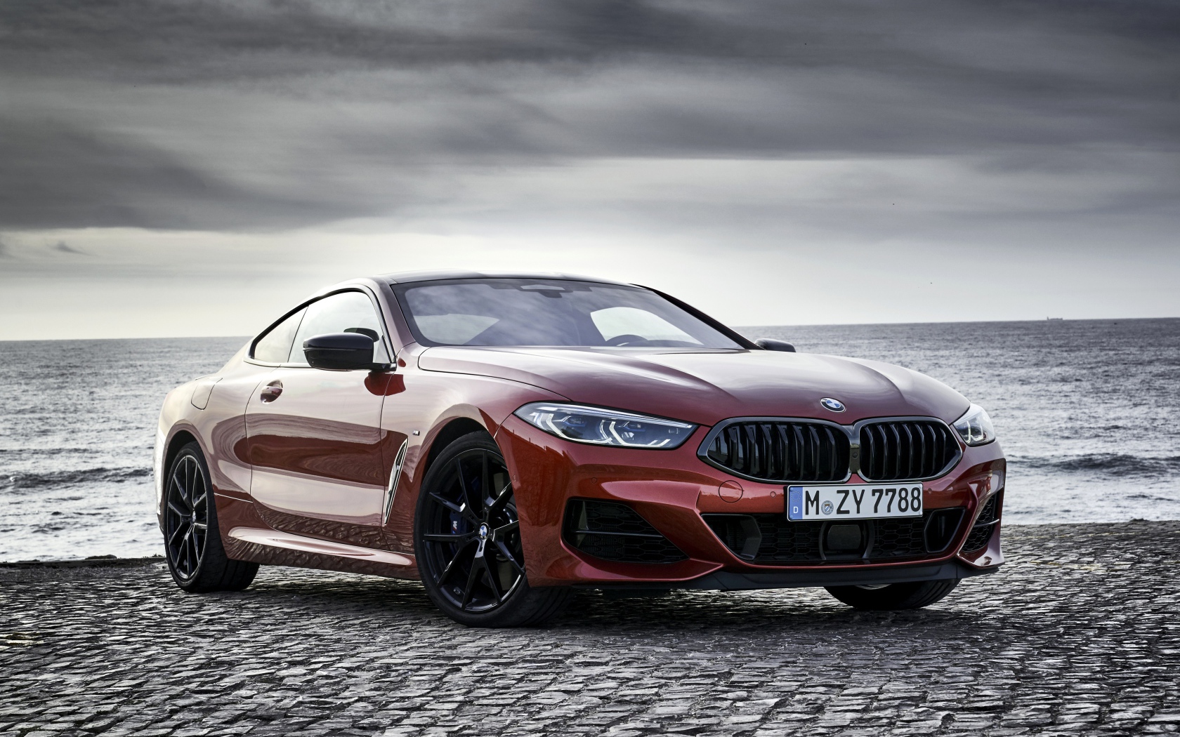 Красный автомобиль BMW 8 Series на фоне моря
