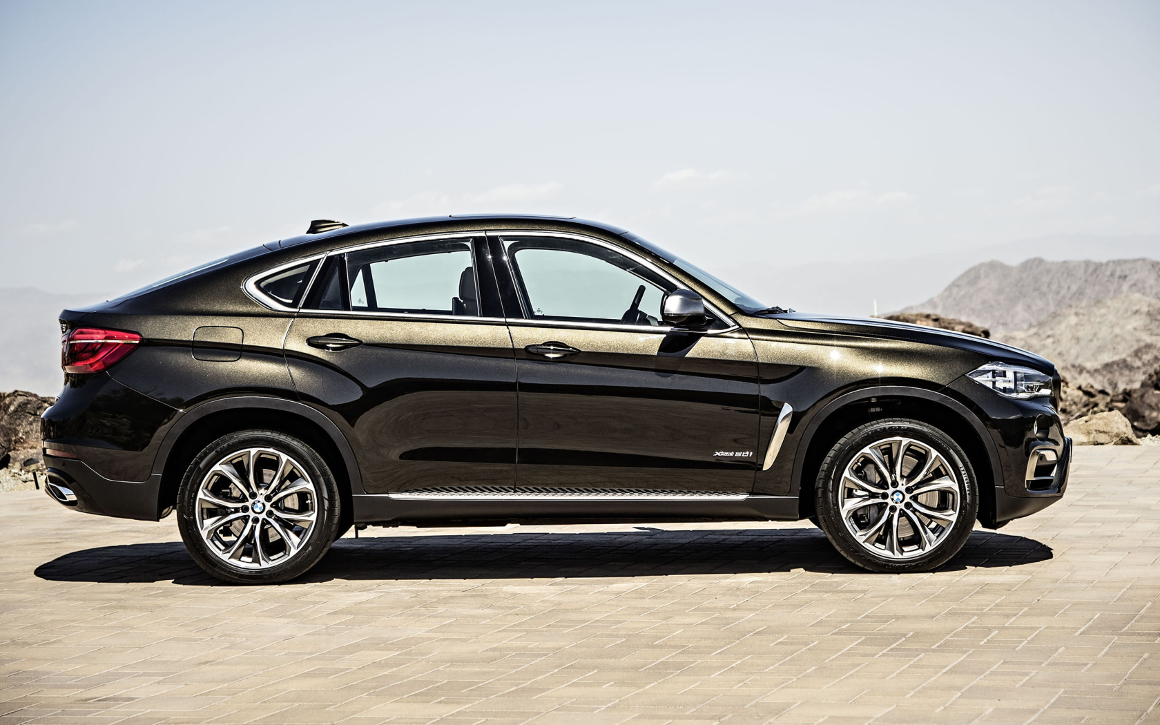 Черный автомобиль BMW X6, 2018 года вид сбоку