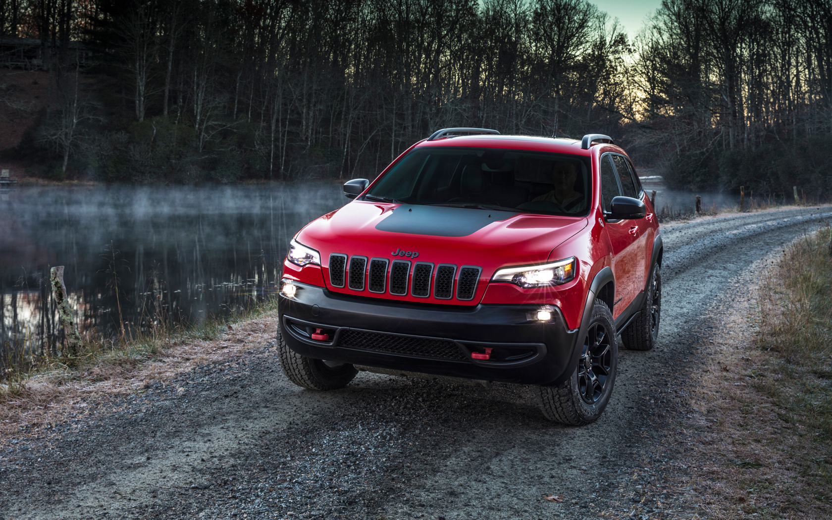 Красный автомобиль Jeep Cherokee Trailhawk, 2019 на дороге у реки