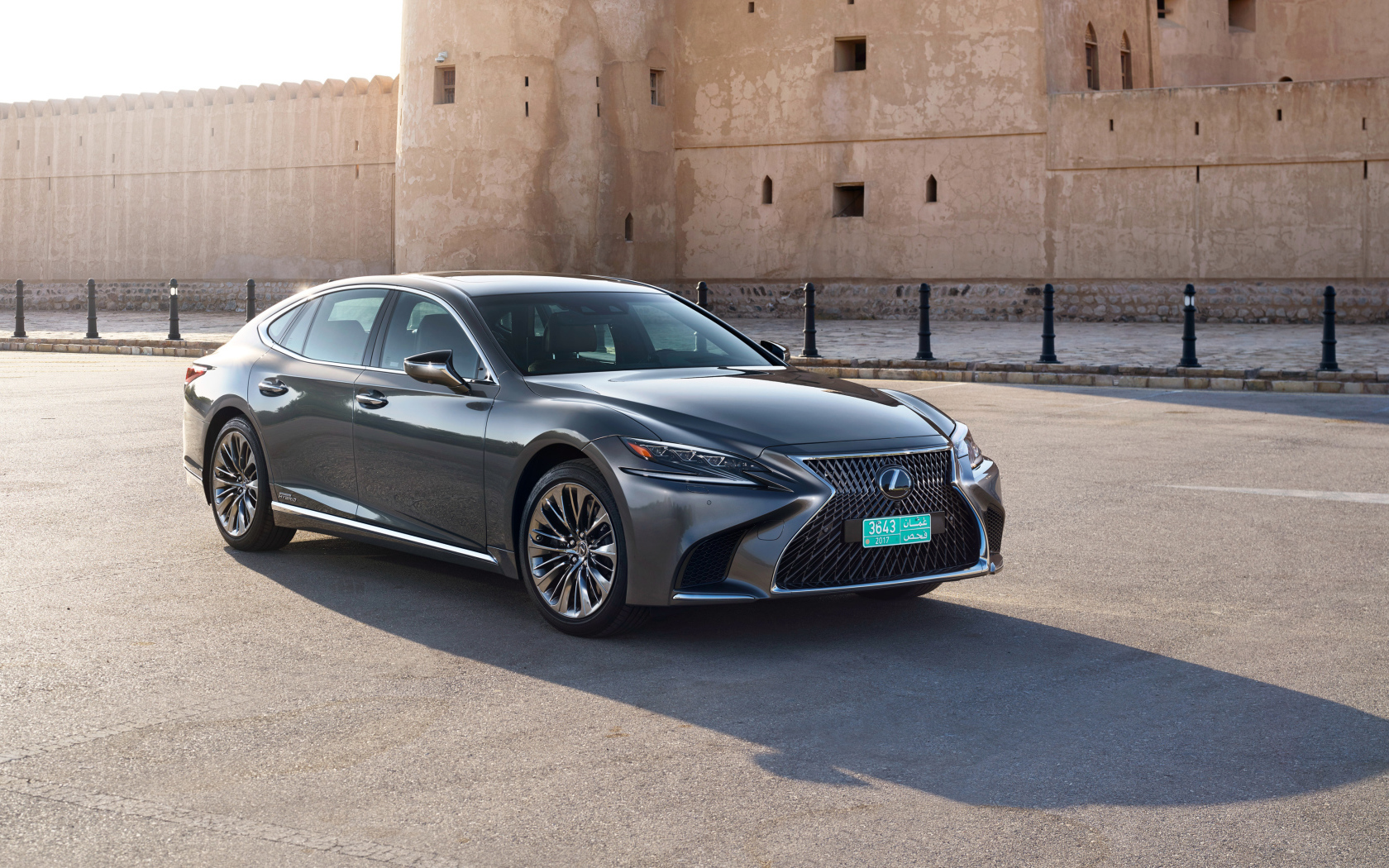 Стильный автомобиль Lexus LS 500h AWD, 2018 на фоне крепости