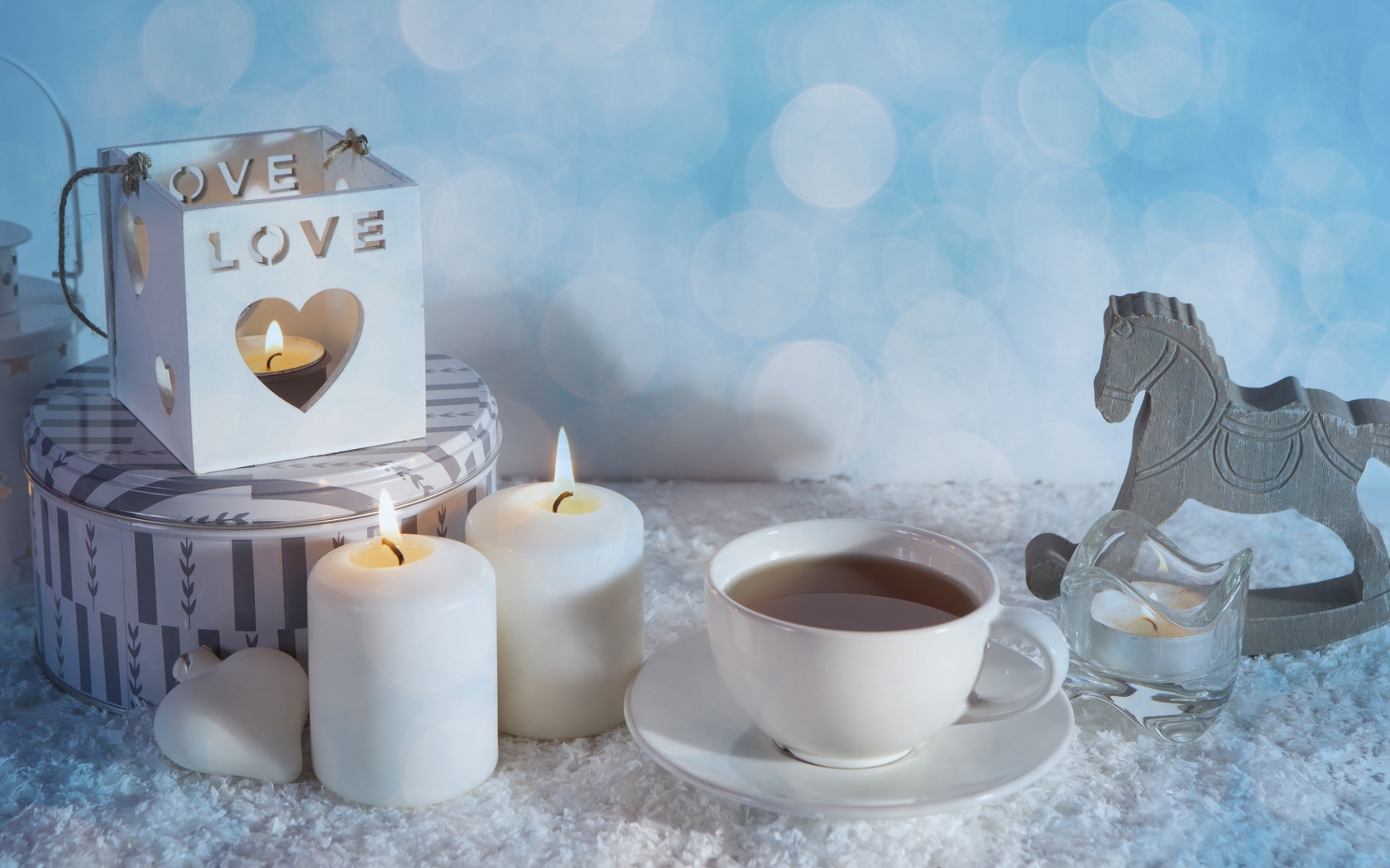Свечи, чашка чая и фигура лошади на столе 