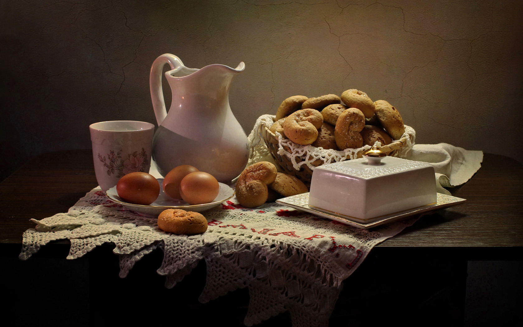 Вареные яйца на столе с кувшином, выпечкой и масленкой 