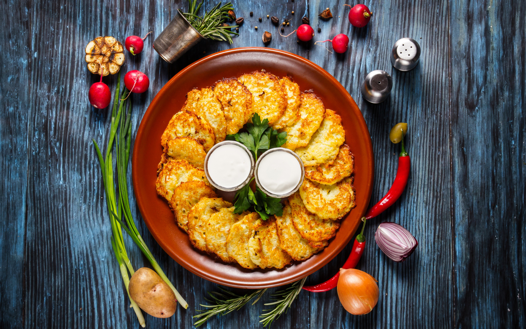 Драники с соусом на тарелке на столе с овощами