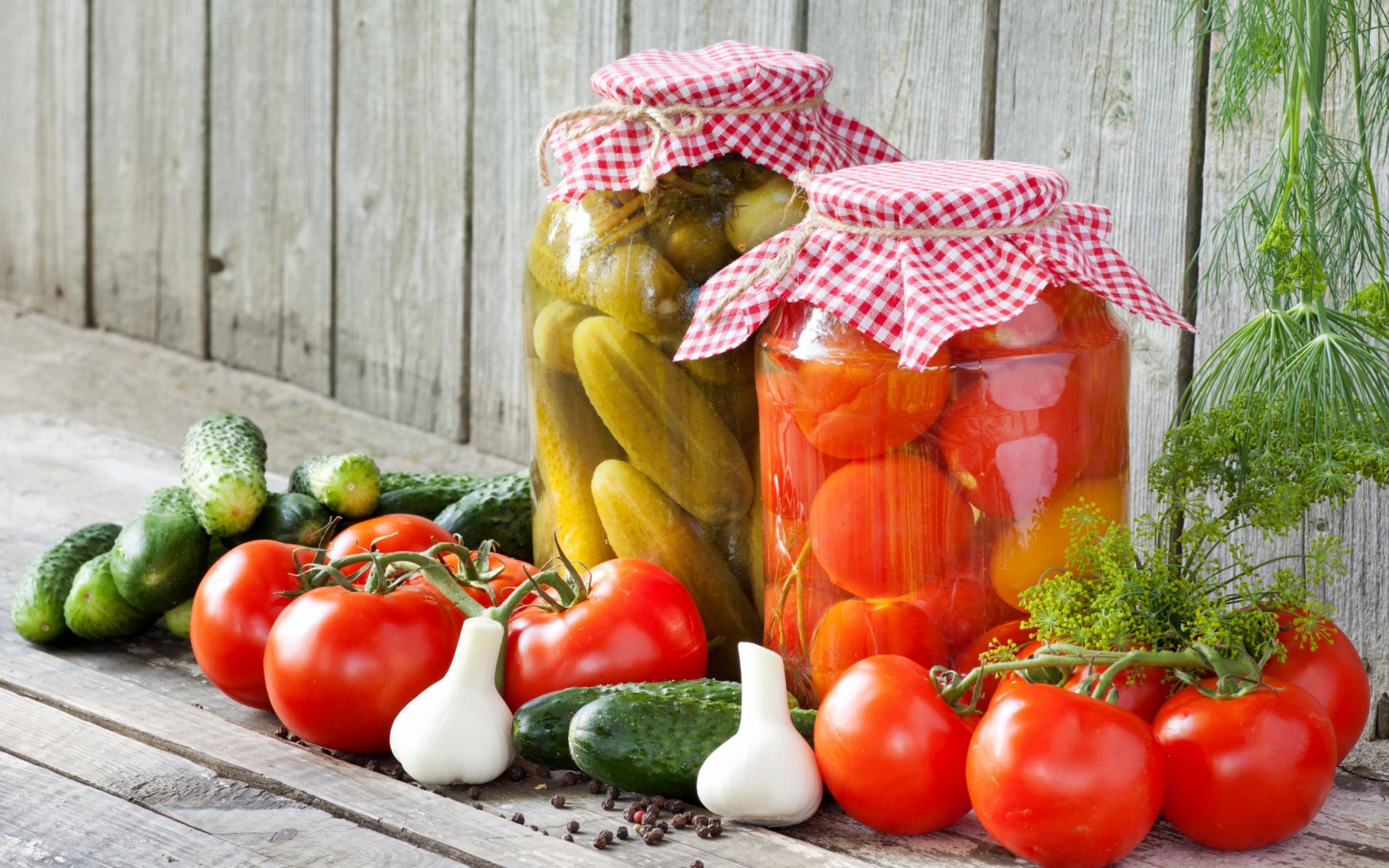 Соленья из огурцов и помидоров с овощами на столе