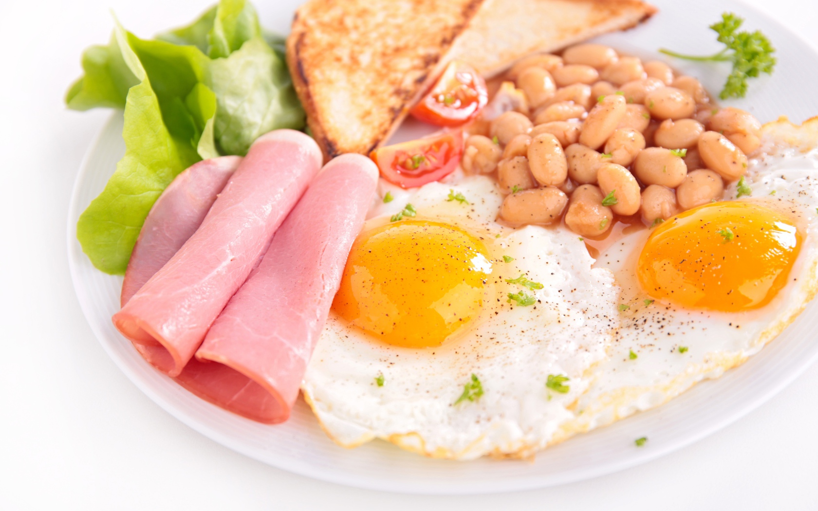 Яичница с беконом, гренками, фасолью и листьями салата на завтрак