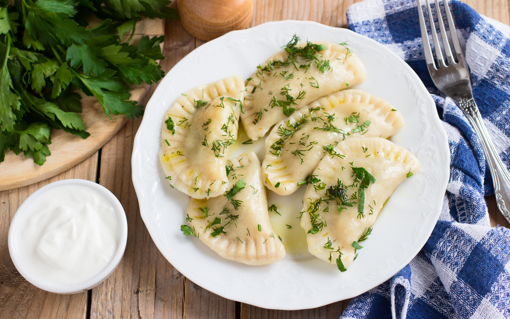 Вареники с зеленью на белой тарелке 