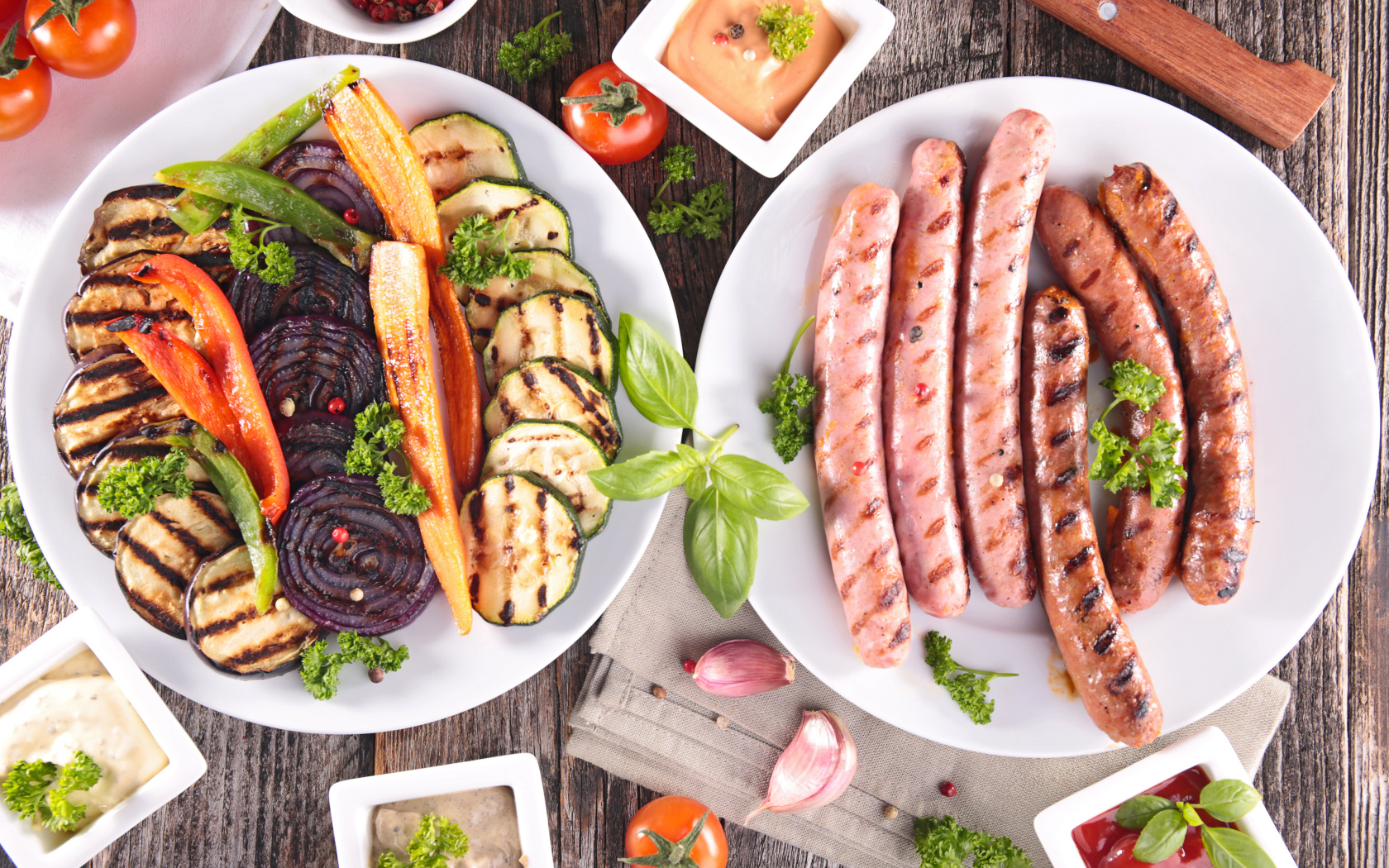 Овощи и сосиски гриль на столе с соусом