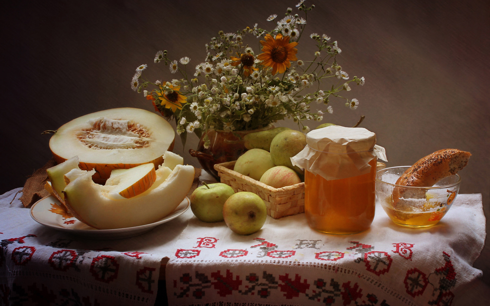 Сочная дыня с яблоками на столе с медом и букетом цветов