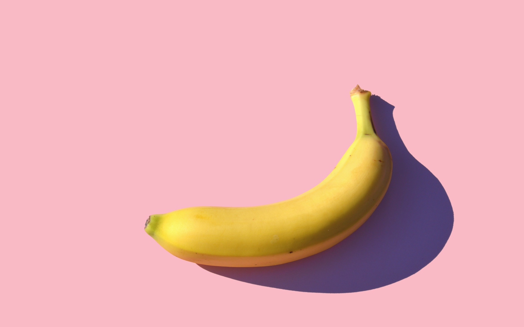 Желтый банан на розовом фоне