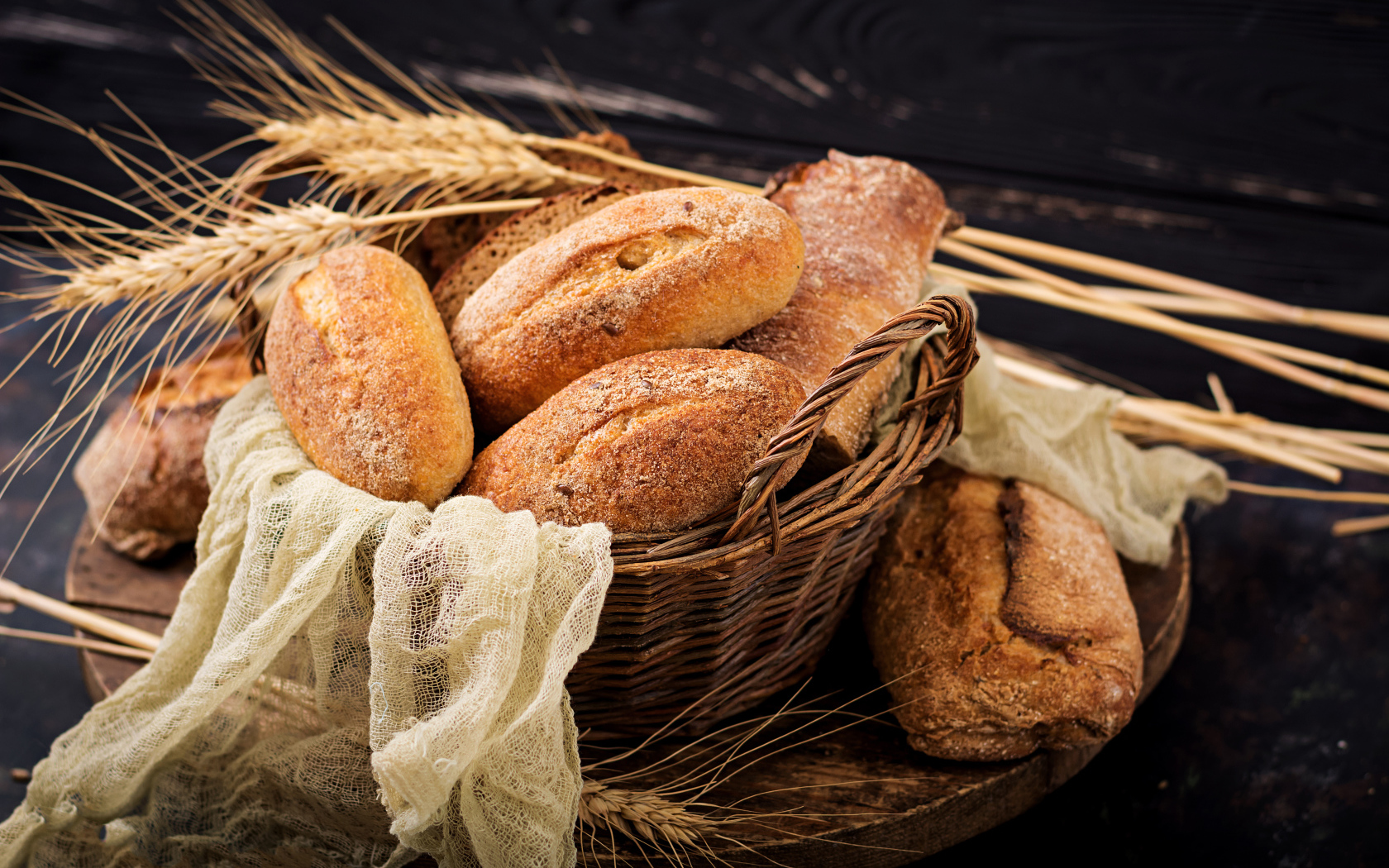 Свежая выпечка в корзине на столе с колосьями пшеницы