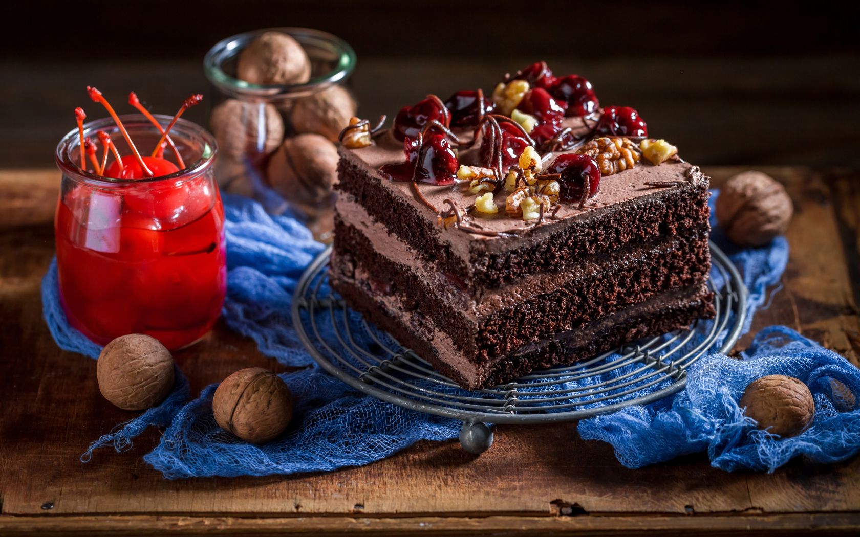 Кусок шоколадного торта на столе с вишнями и грецкими орехами