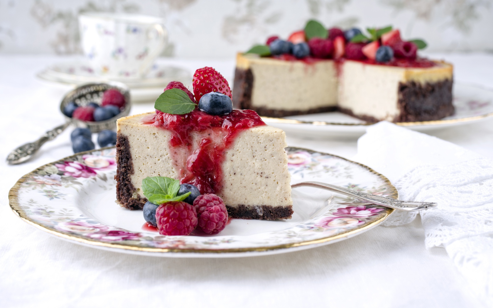 Чизкейк на столе с ягодами малины, черники и клубники